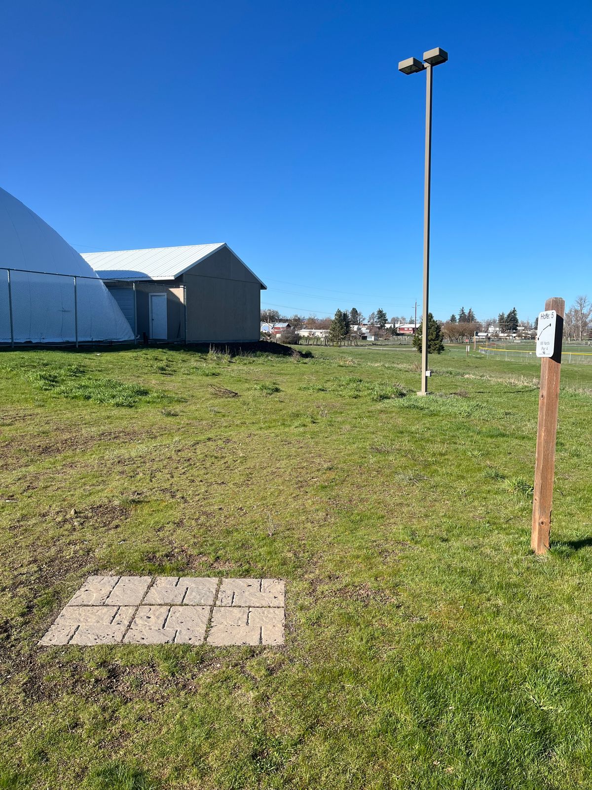 Hole 5 tee pad. basket is beyond the buildings to the left