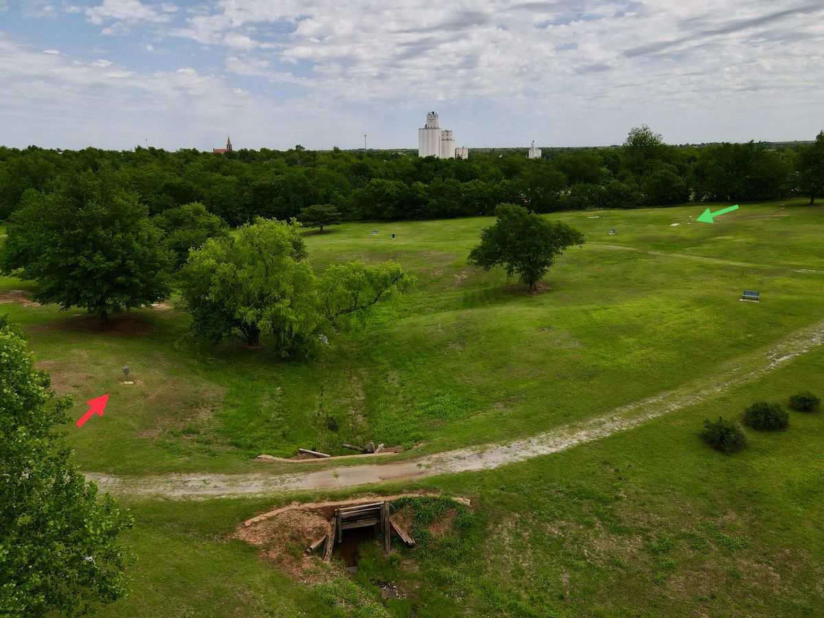Aerial of hole 4 from over the creek, showing the basket behind the trees (red) and tee pad (green)