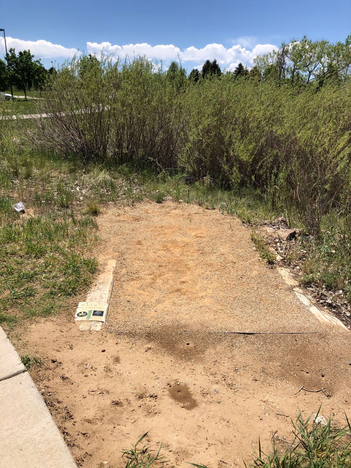 Hole 1 at the North end of the parking lot. There is a small sign just off the sidewalk.