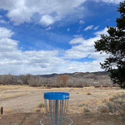Looking back onto hole 1 tee pad from behind the basket with a view of S mountain in the background.