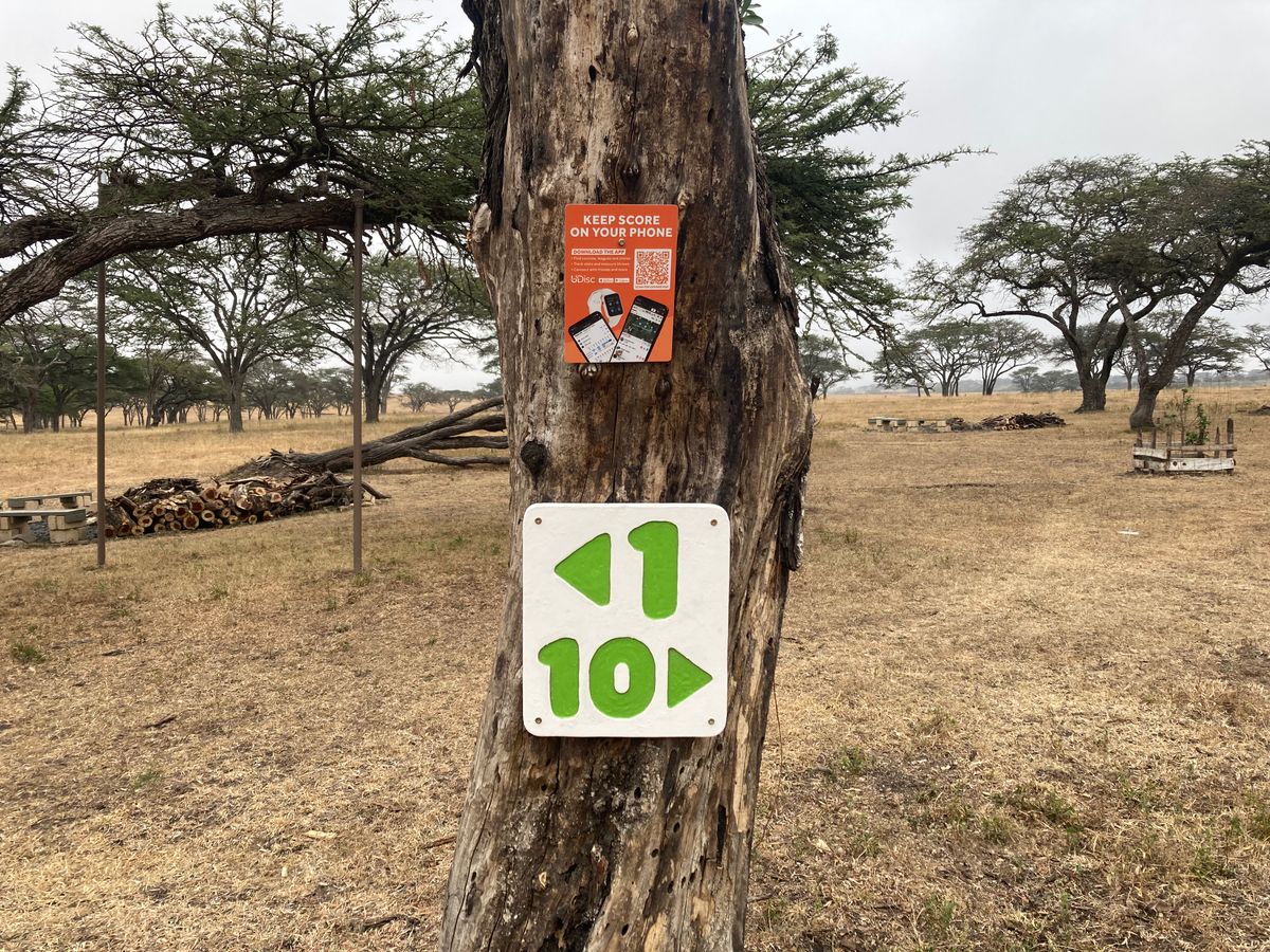 UDisc sign and directions to the front and back 9 on the corner of the parking lot.