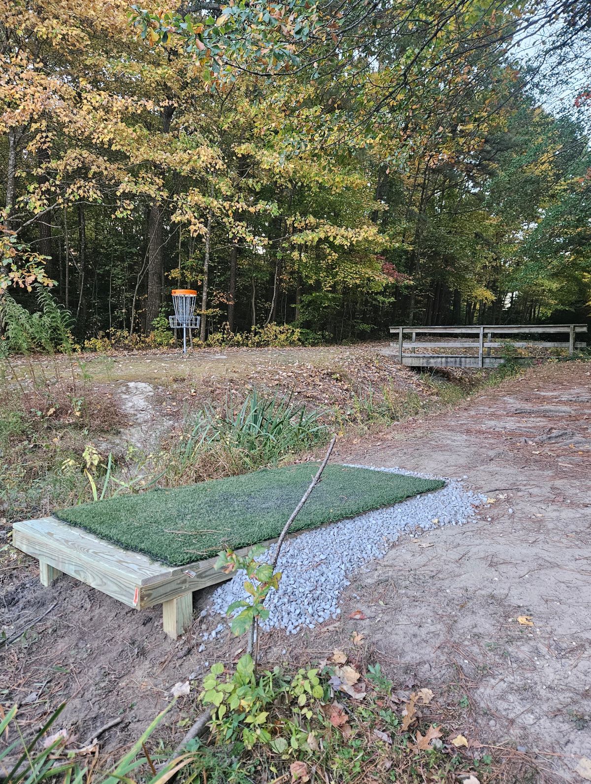 Side view of hole 9's tee pad. Hole 8/16 basket visible in the background.
