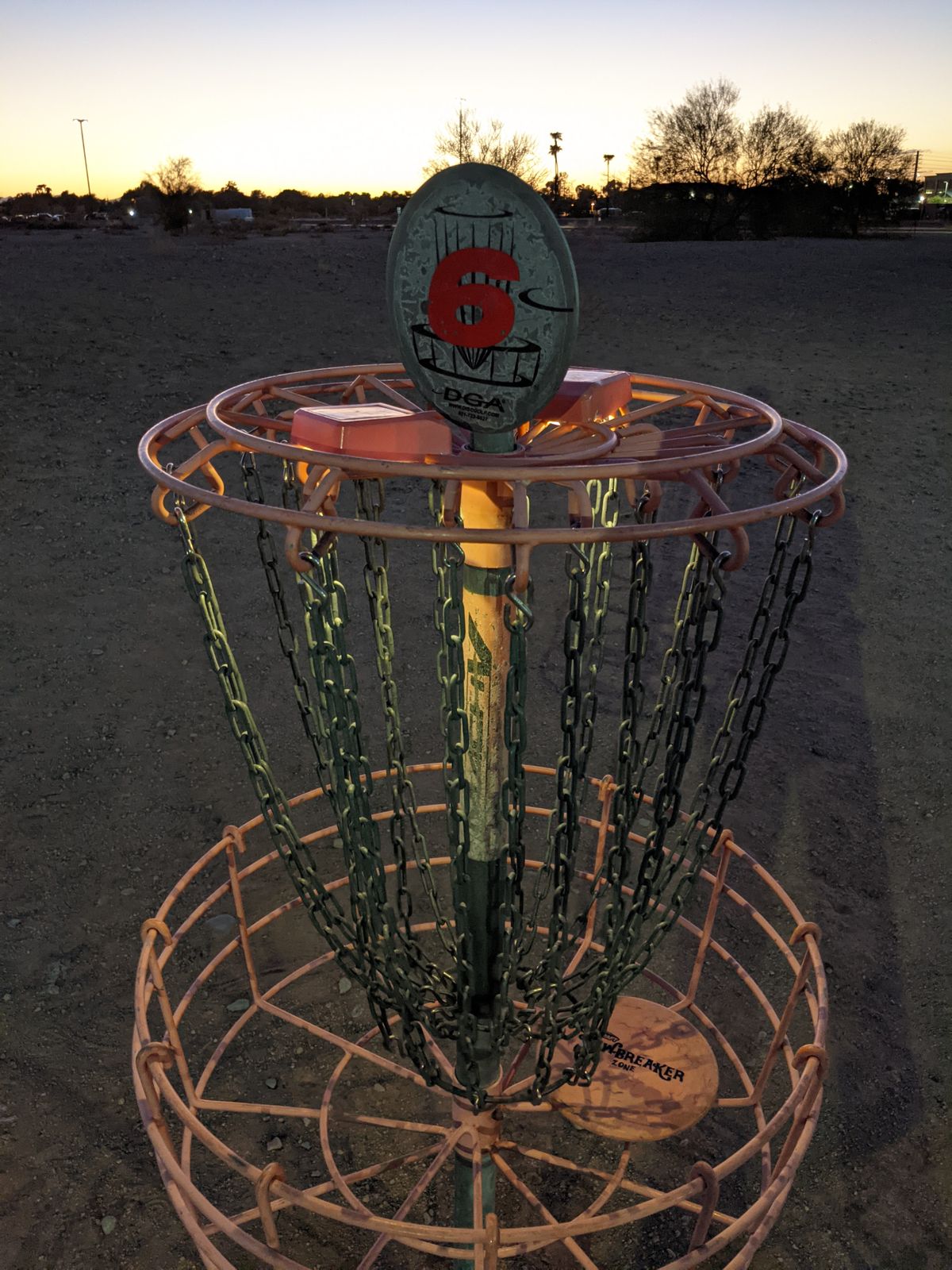 Solar lights shining on the basket at dusk. With the parking lot lights, exterior rec center lights, and tennis court lights you can get a quick round in during the evening and still see well enough to play.