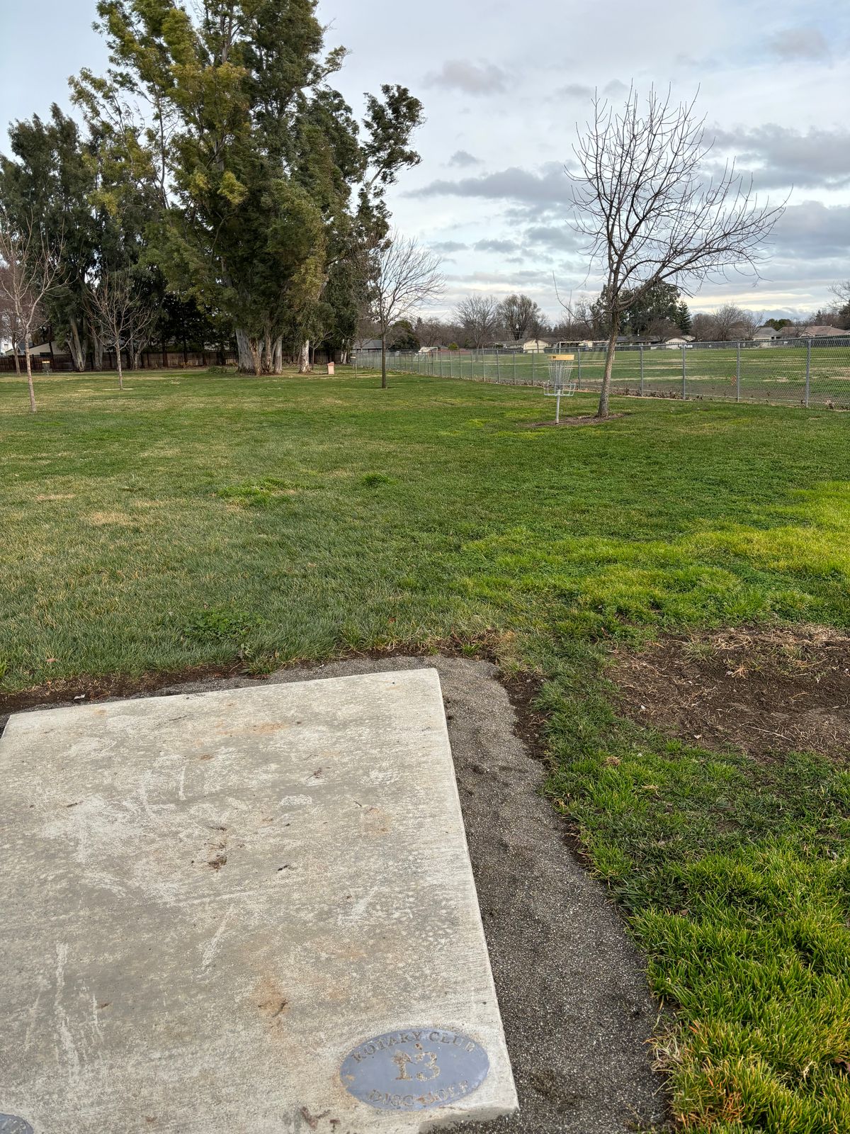 13 tee pad.  Throws to 2 target.  Over middle school fence is OB.