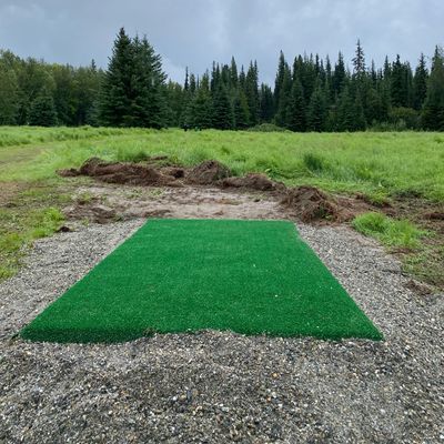 Hole 8 tee pad, basket located behind two spruce trees in the distance