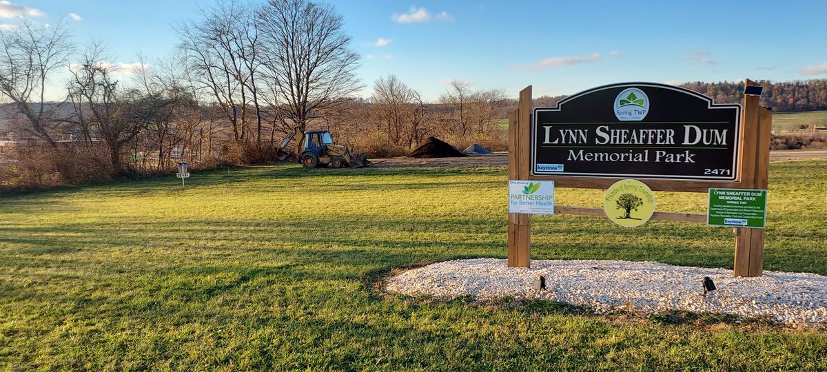Entrance sign to park and practice basket to the left.  Parking nearby