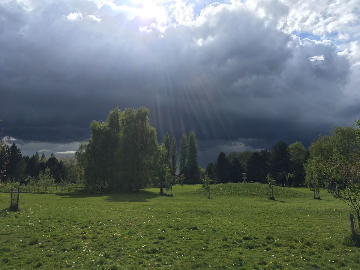 Liquid sunshine and an ominous sky. View from the 6th fairway towards the 3rd basket on the mound.