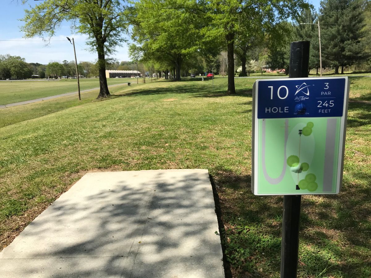 No. 10 tee looking at basket behind trees. Plays along busy street on right.