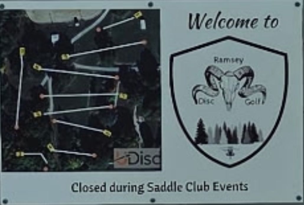 Course sign located on the north side of the concrete building next to tee pad one.