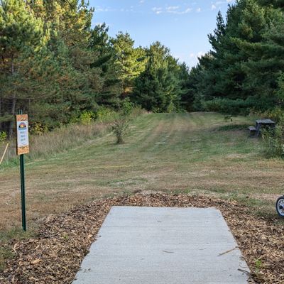 Tee of two. This hole plays down hill and to the left. There are numerous mature white pines guarding circle one and two. I am also convinced the guardian white pine has some form of plastic magnetism.