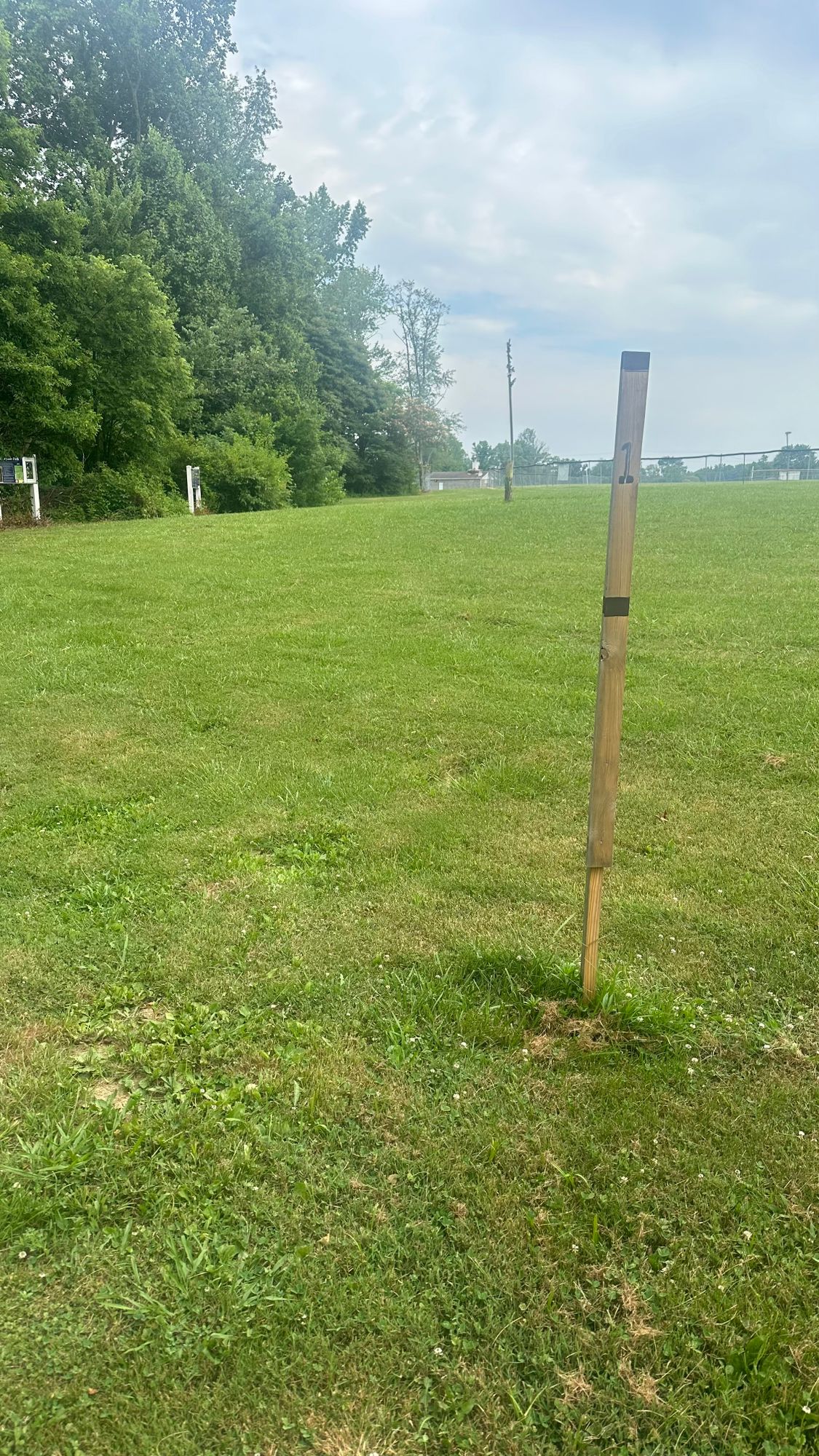Teepad Hole 1

Softball field is Out of bounds.
Rough area left is very thick.
Basket tucked left