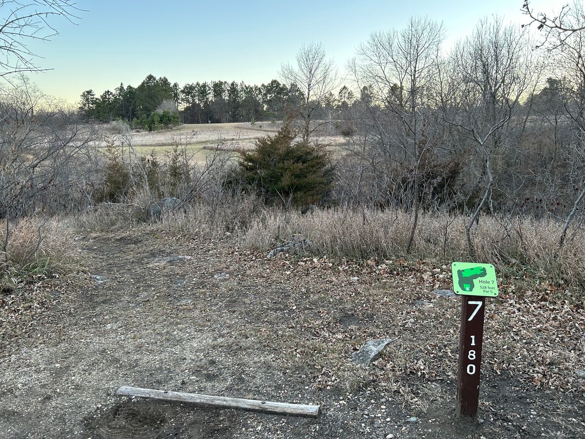 Hole 7 has a short carry over trees/ruff , then it makes a sharp dog leg to to the right .