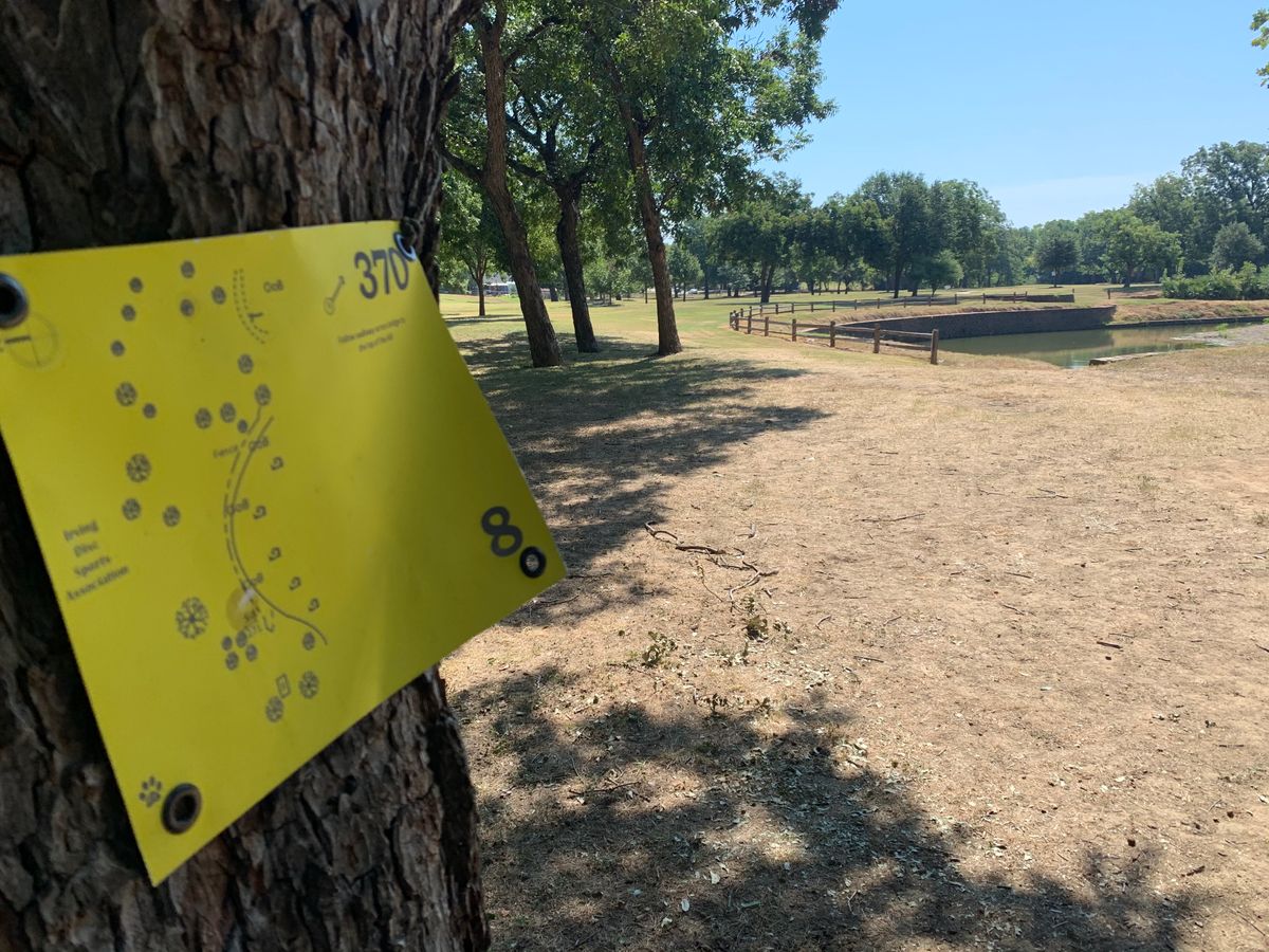 Hole 8. Signage on the tree to the left of the tee pad. Creek to the right.