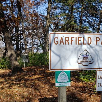 Park sign overlooks hole ones basket.