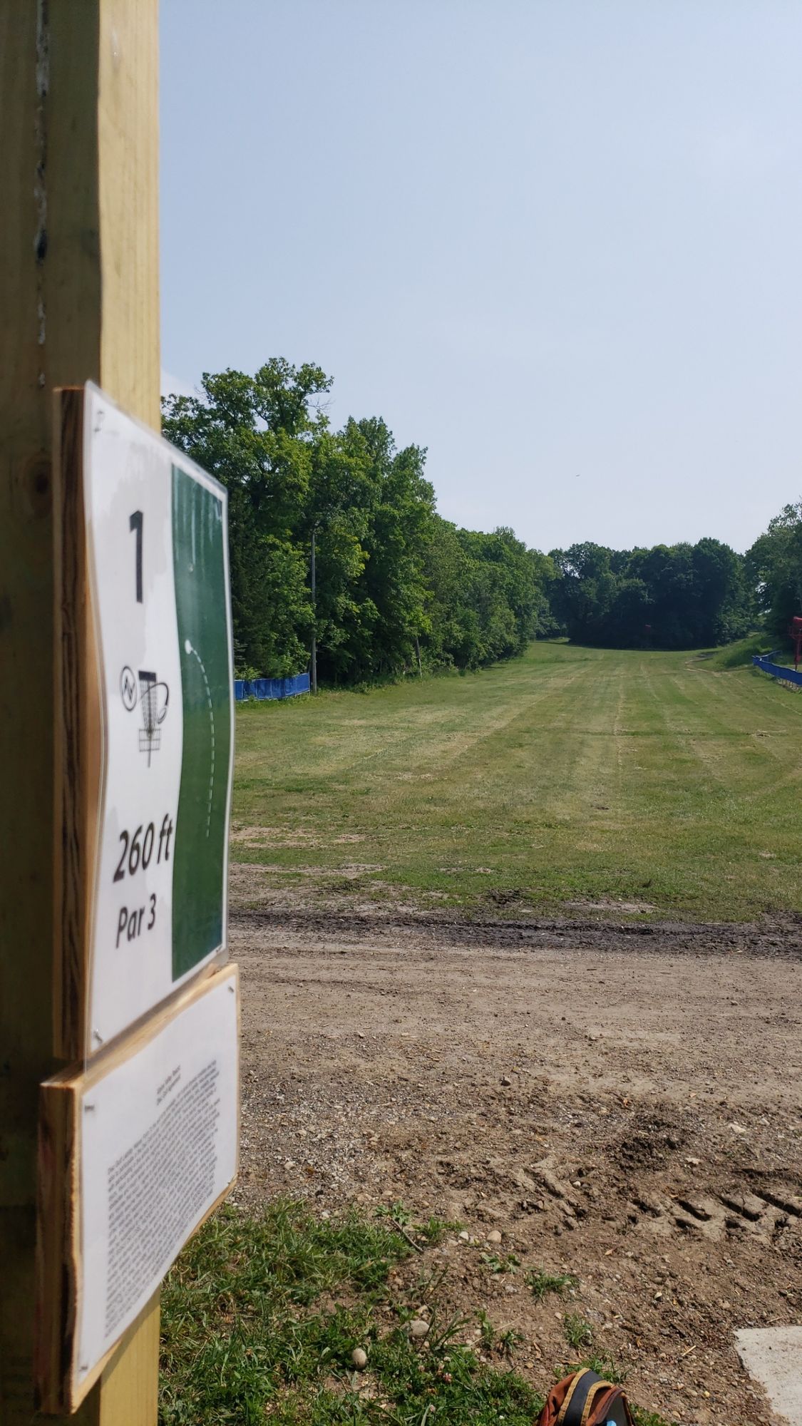 Hole 1 basket slightly tucked into treeline on the left