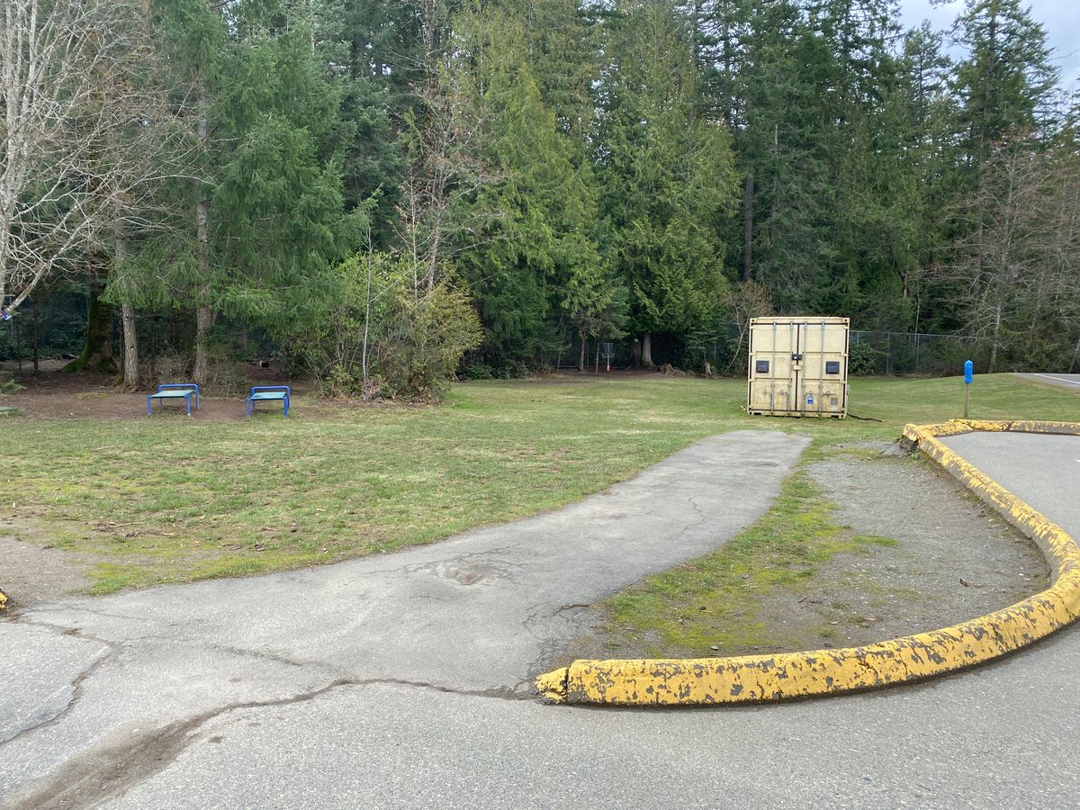Hole 1 fairway.  All black top Paths are OB.  Target Dan Walker Basket is in trees to slight left behind the  container.