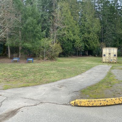 Hole 1 fairway.  All black top Paths are OB.  Target Dan Walker Basket is in trees to slight left behind the  container.