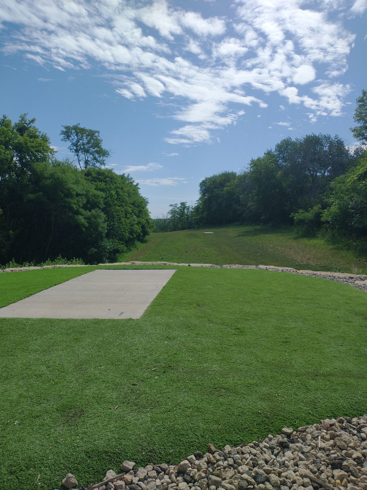 Hole 1 has a cement teepad and is surrounded by turf grass and rocks.