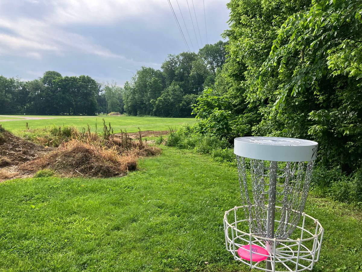 Hole 18 basket POV. Basket tucked in front of tree line. OB is 20ft to the right of basket.