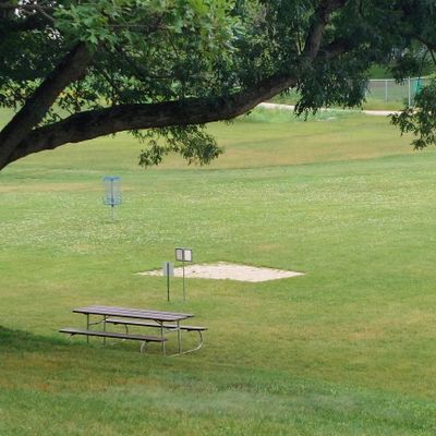 Hole #1 (taken from parking lot), practice basket in the background for a quick warm up. Only real defined tee pad (the others have signs)