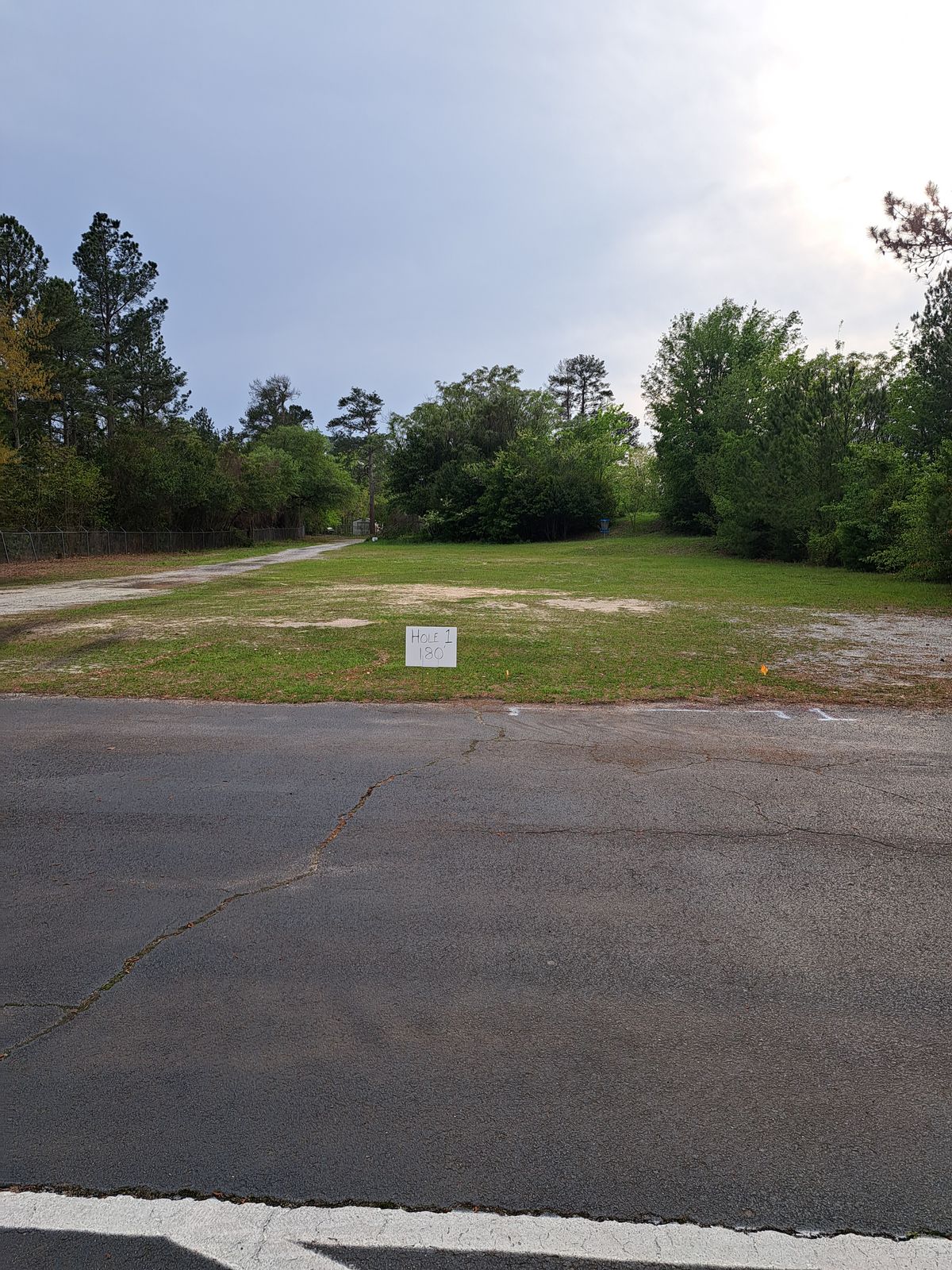 Hole 1. The road on left side leads to hole 2. Follow road through gate then turn left follow along right-side of baseball field.