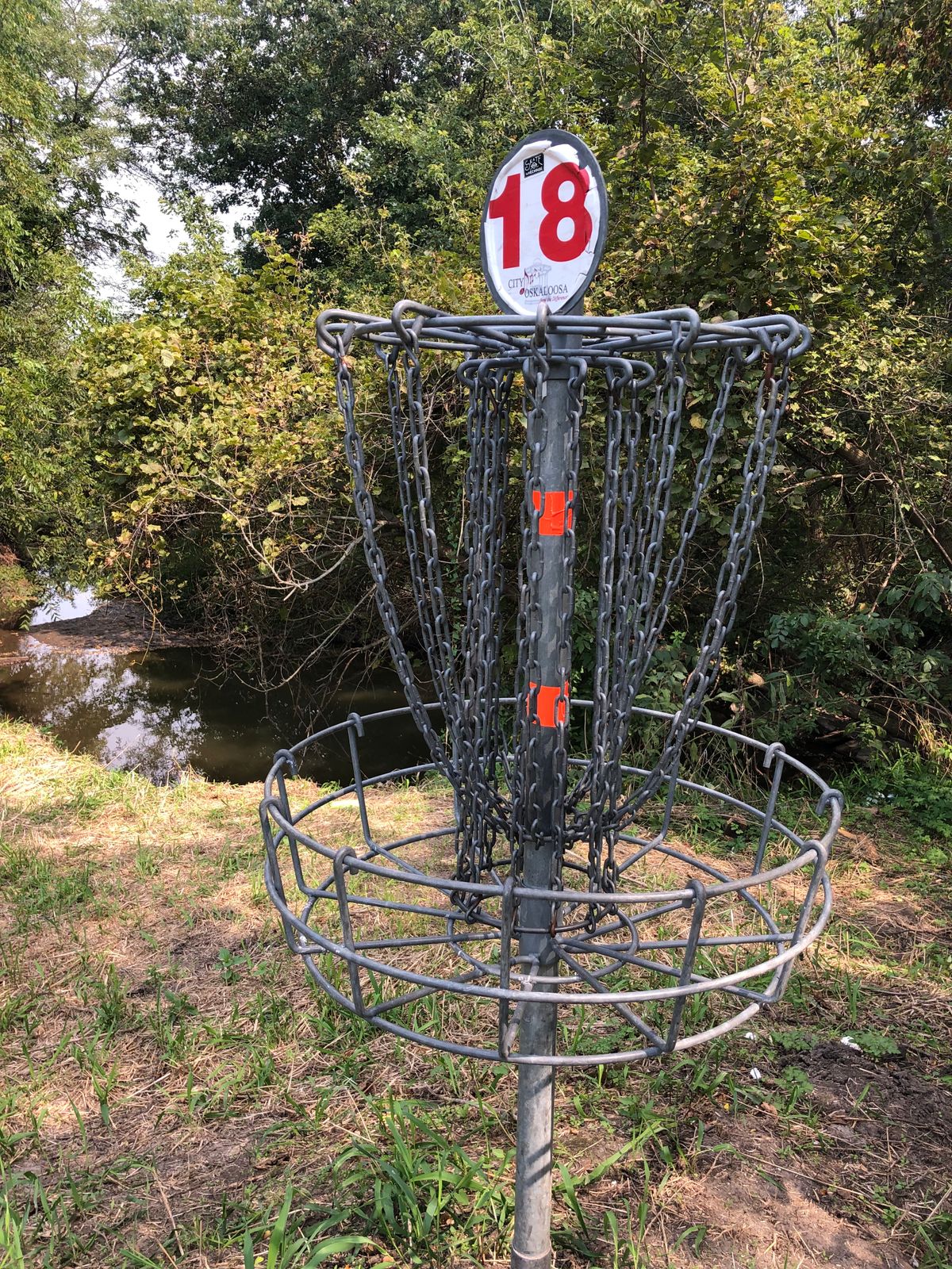 Basket on a mound with steep dropoff to murky pond. Good bye putter if you run it.