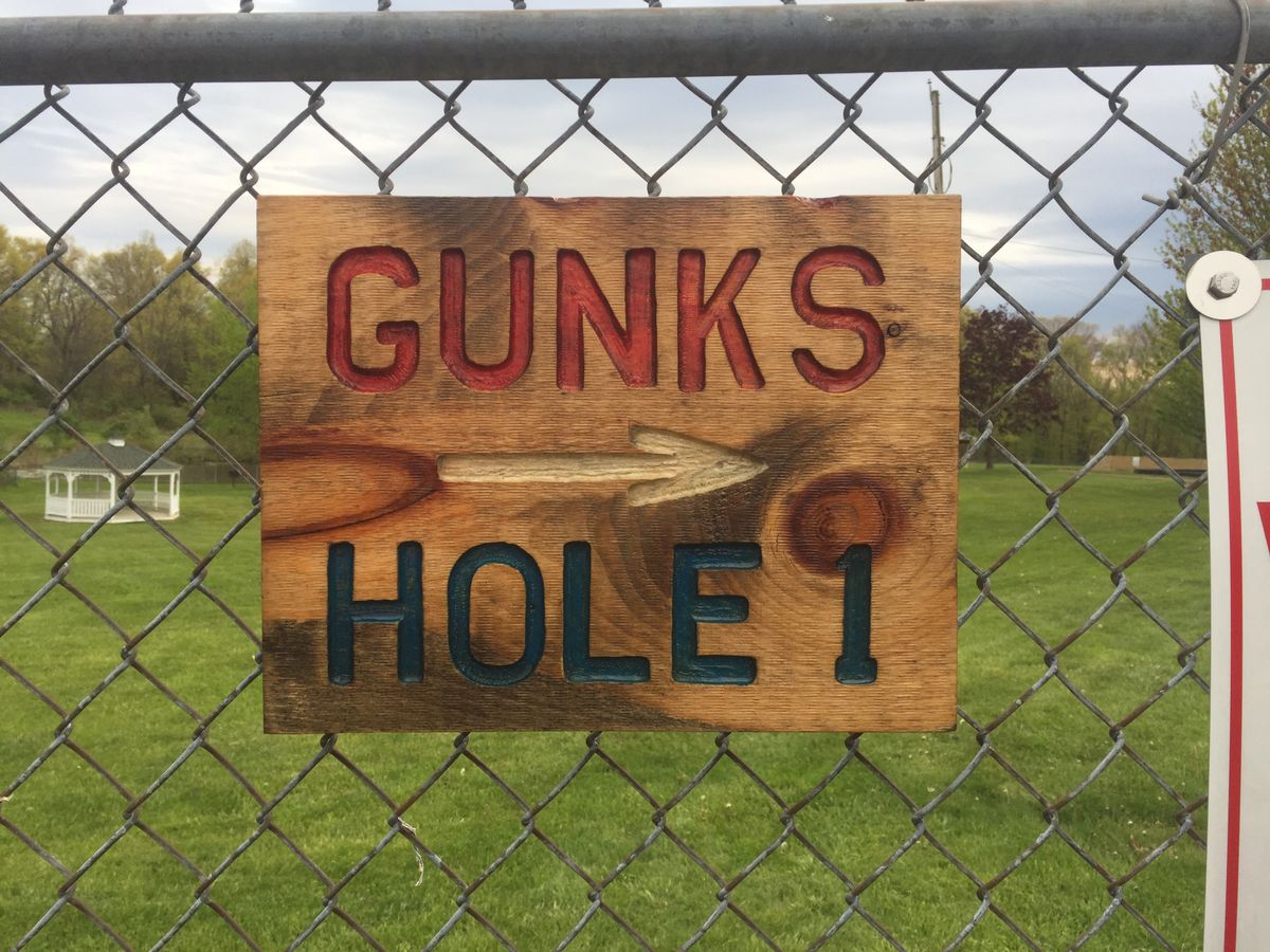 parking lot sign showing the direction to hole one