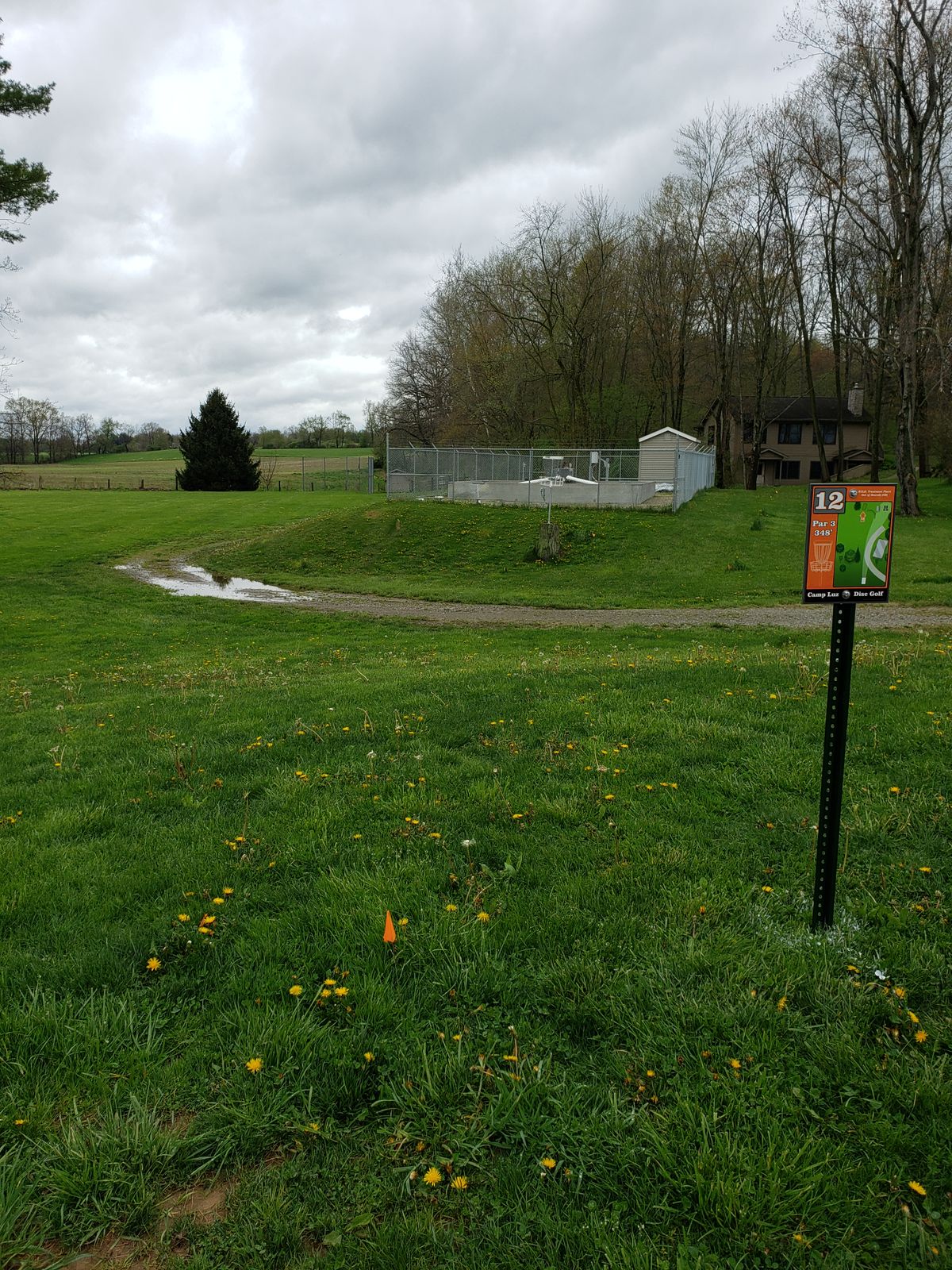 Longest hole at Camp Luz.  Basket is to the right of the shed at the fencerow.  The basket visible in front of the wastewater plant is the stump basket for hole 11.  Wastewater plant is out of bounds.  Contact the camp office for for assistance if discs are stuck inside.