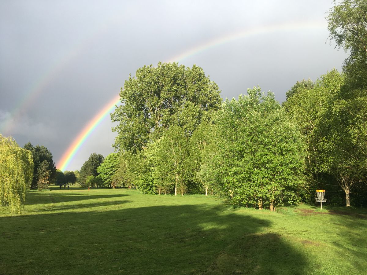 Looking back down the lush 18th fairway underneath a rainbow in springtime.