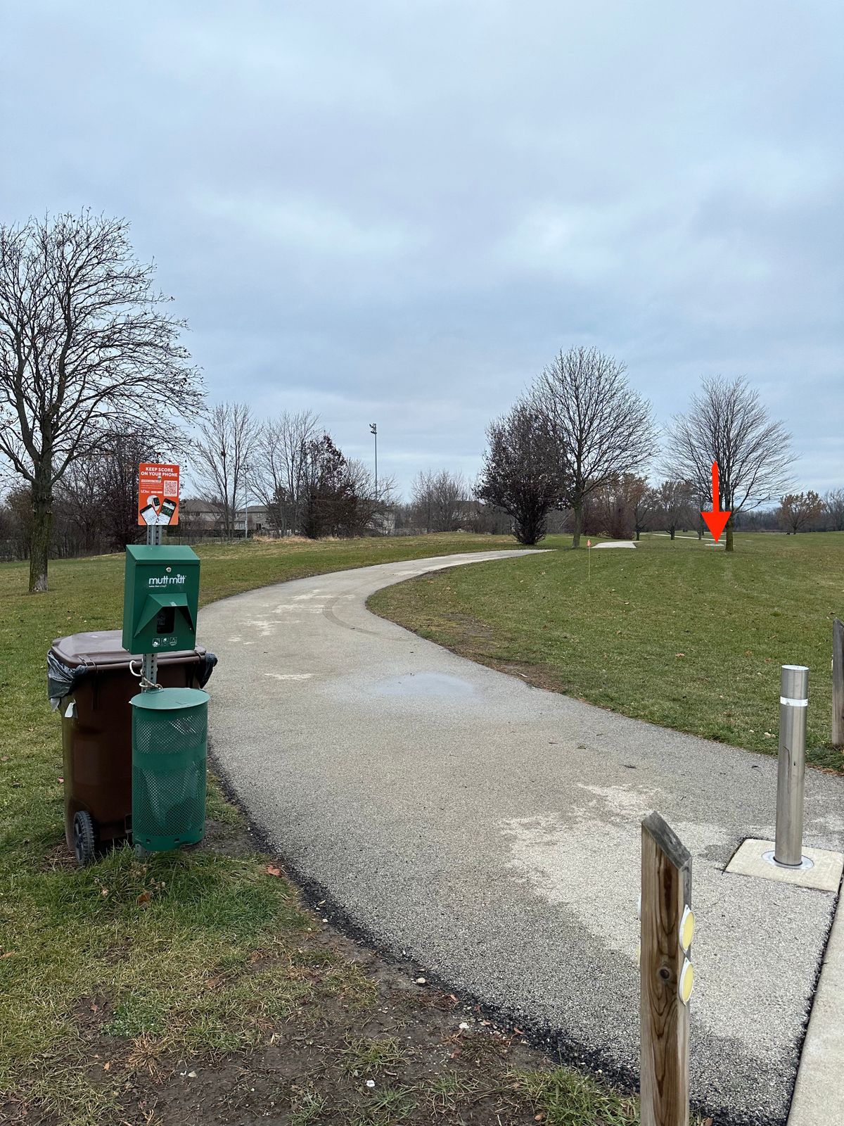 UDisc sign near parking lot looking toward hole 1 tee pad (red arrow)