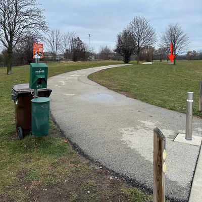 UDisc sign near parking lot looking toward hole 1 tee pad (red arrow)