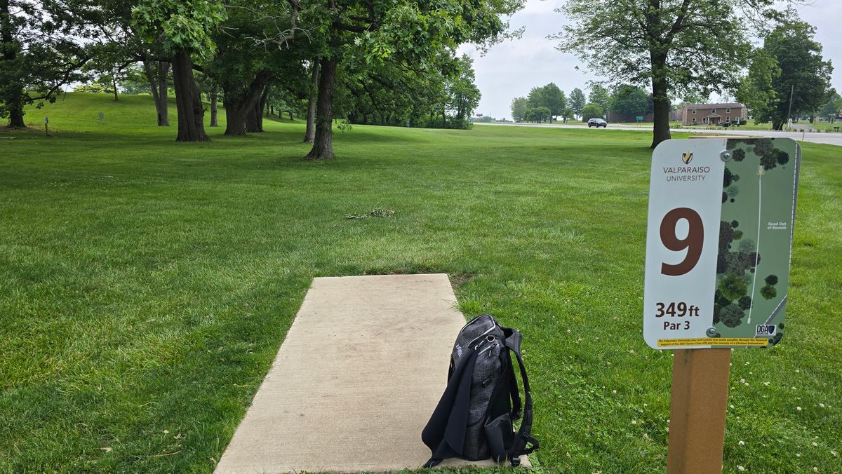 Hole 9 - Basket is straight ahead with some low hanging tree branches to contend with and U.S. 30 on the right. The Hole 3 basket and Hole 4 teepad can be seen to the left.