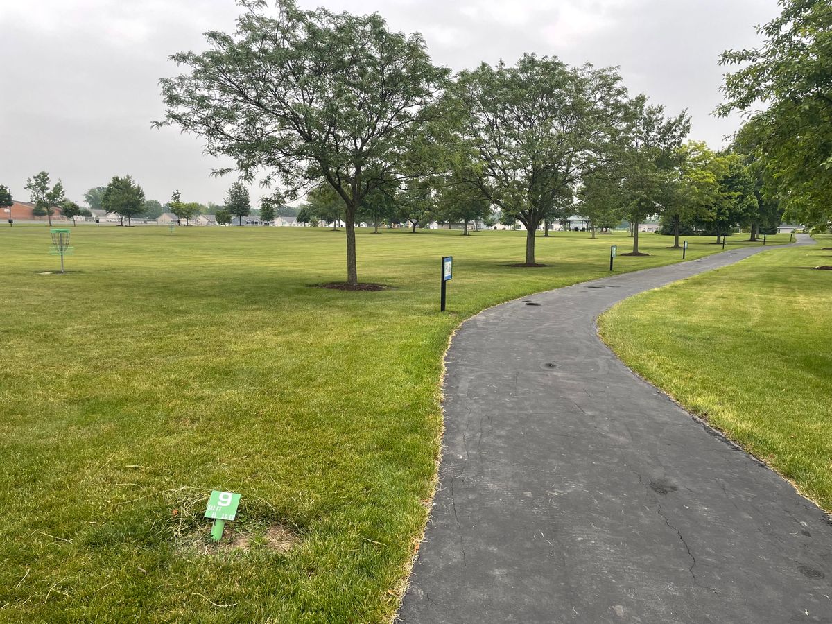 9th hole. Straight shot towards the cage is between the trees, below the branches and above the sign
