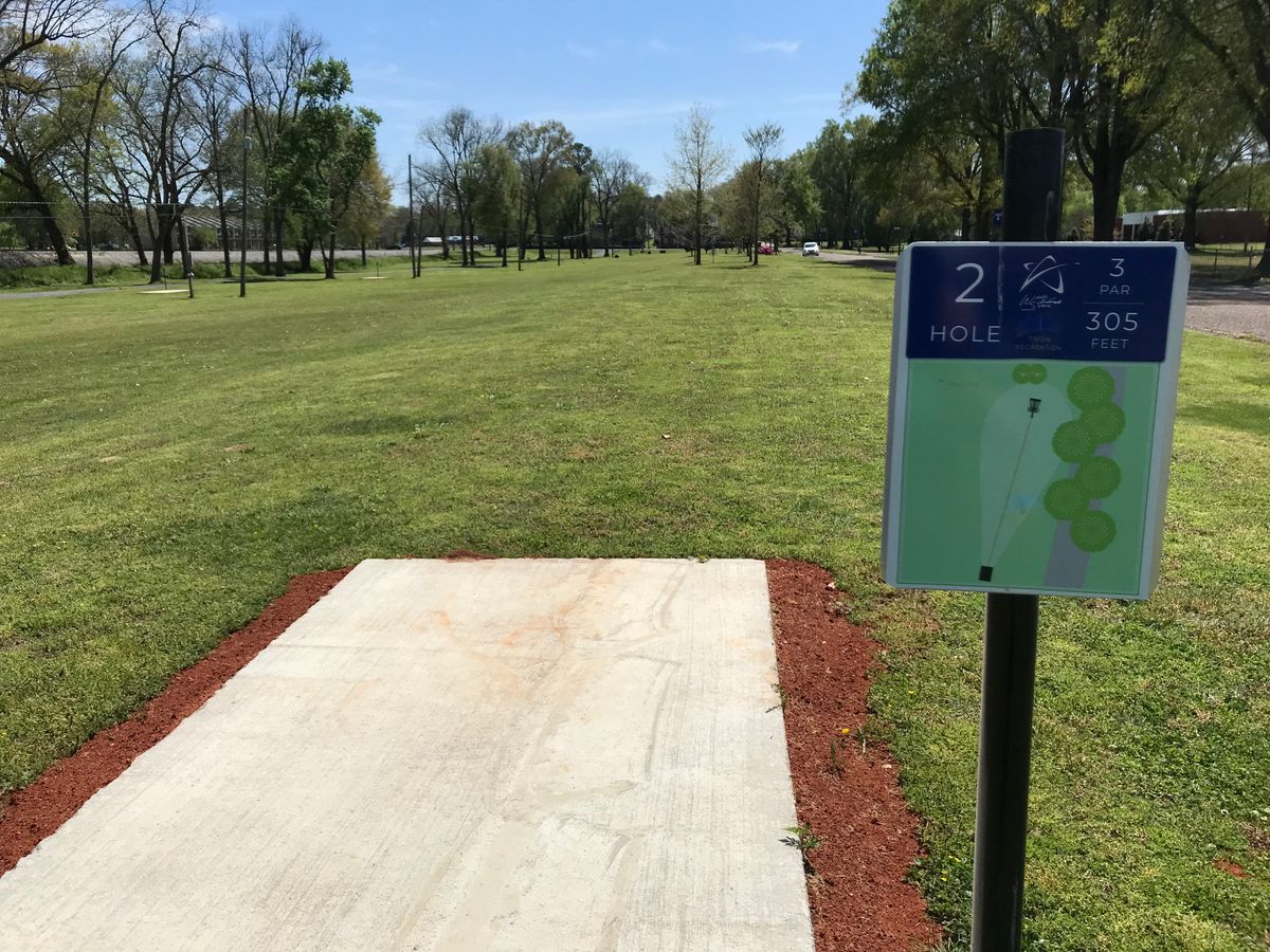 No. 2 tee. Basket straight ahead behind trees. Road plays along right..