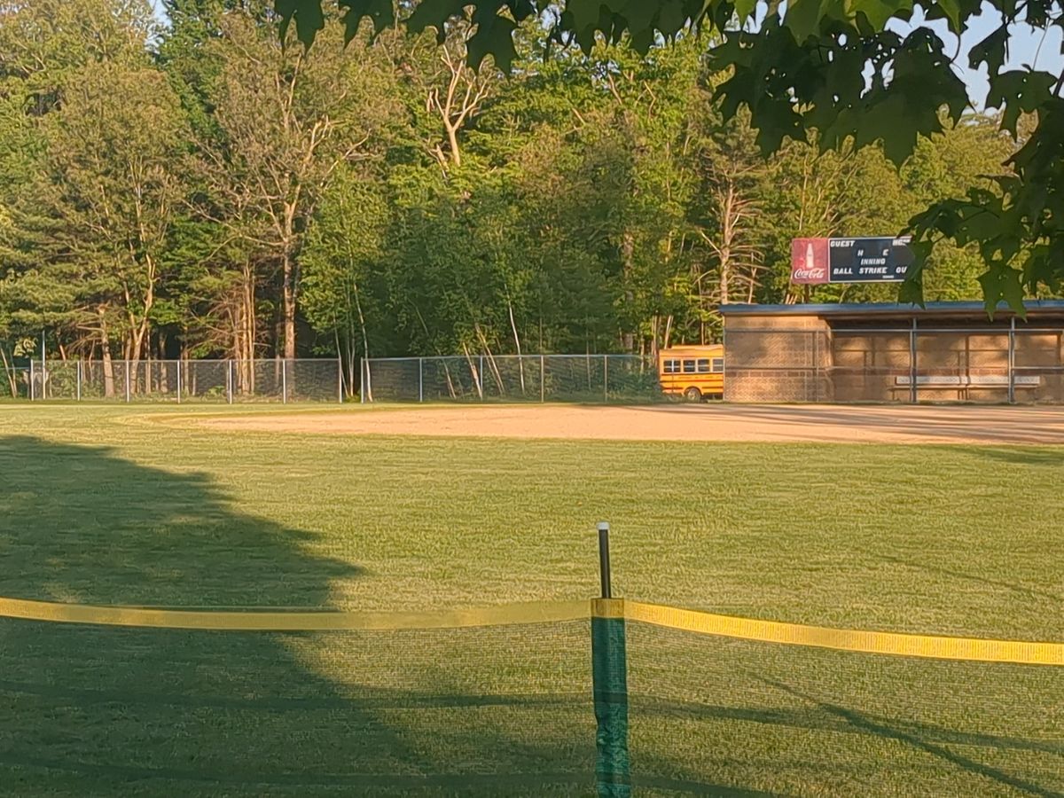 Entrance is the gap in the fence to the left of the dugout.