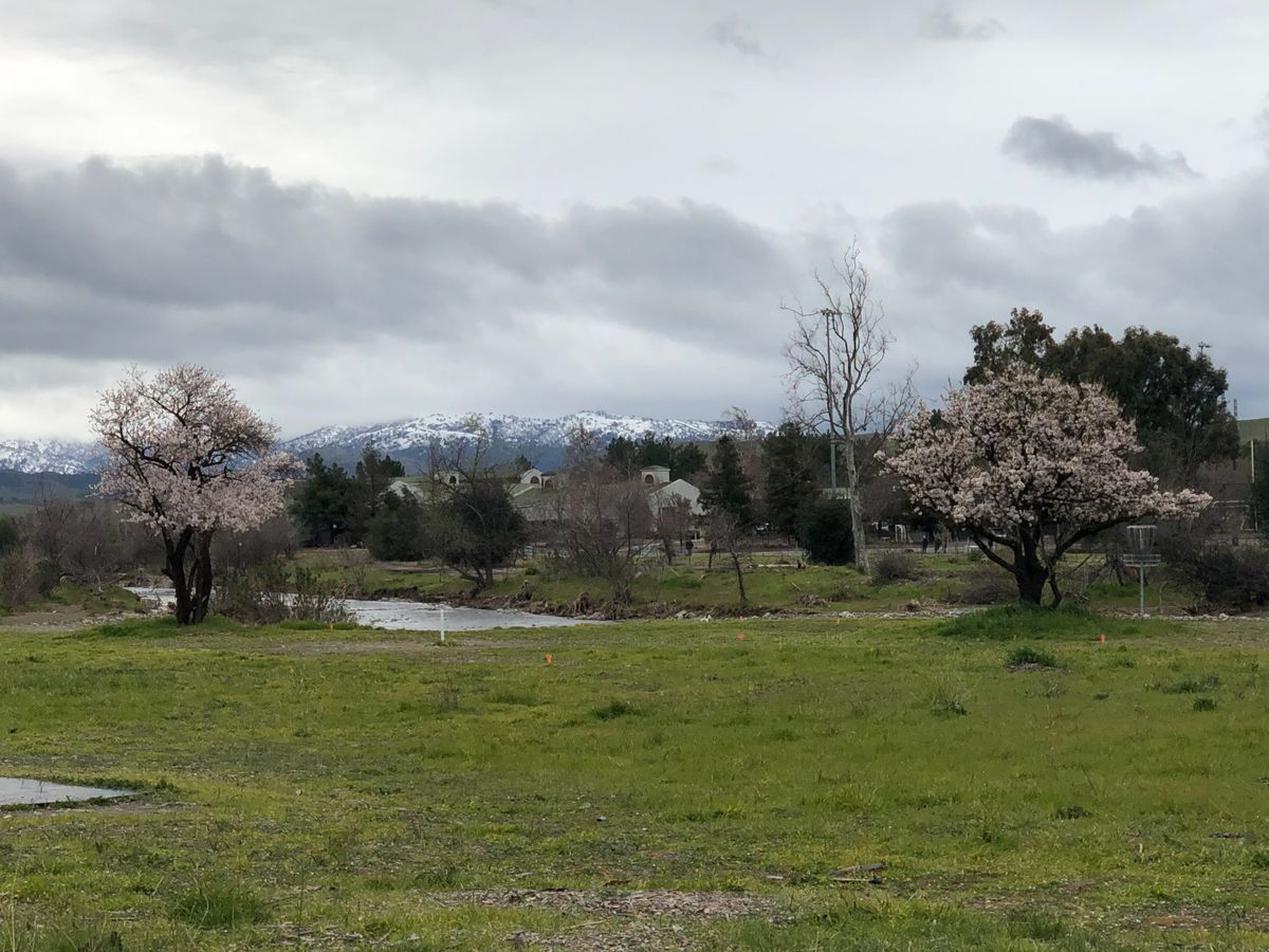 Hole 7 with the trees in bloom and the mountains dusted with snow