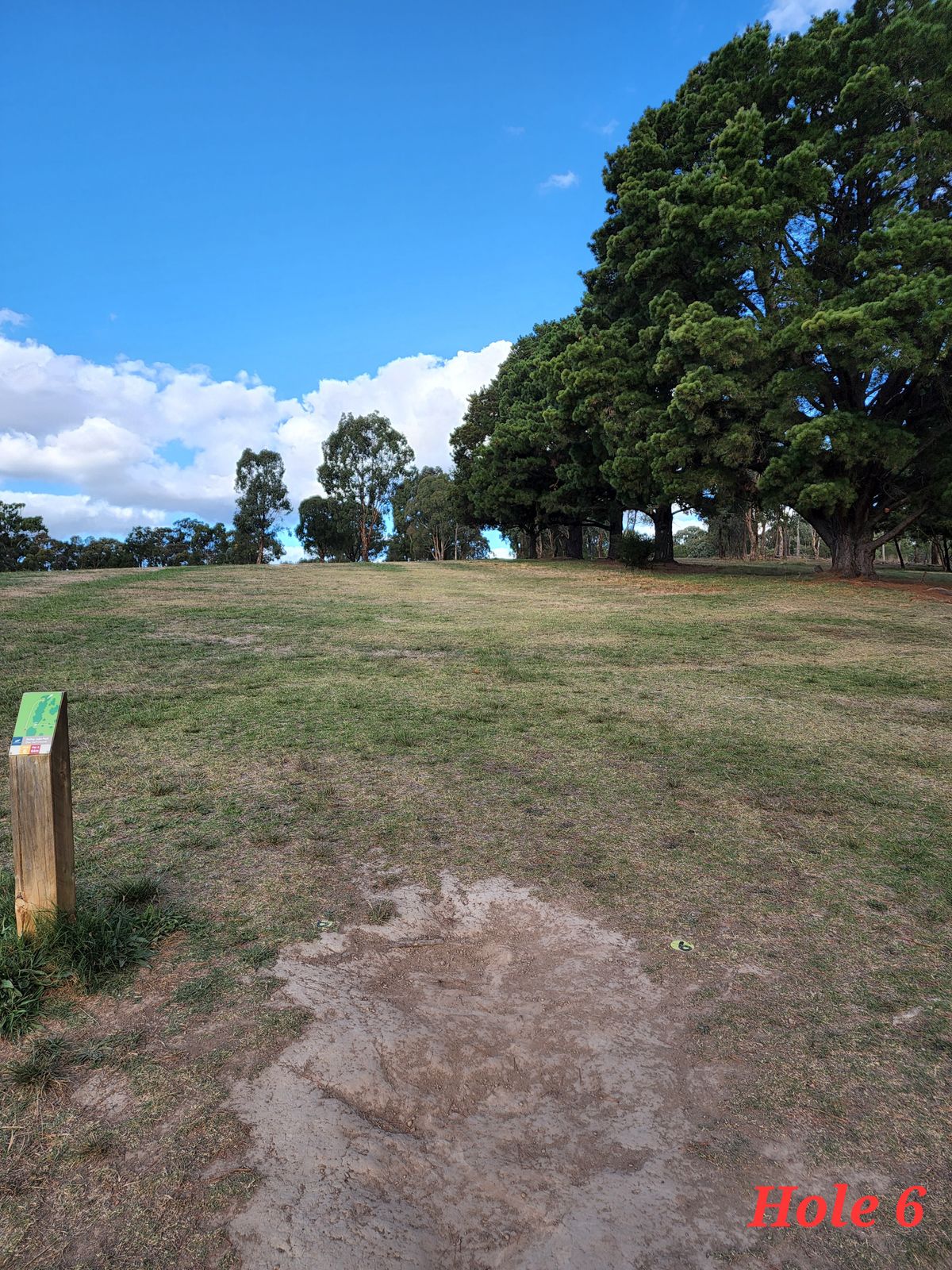 Uphill forehand hyzer shot. Use the open space to the left to swing the disc through the gap to the left of the basket.