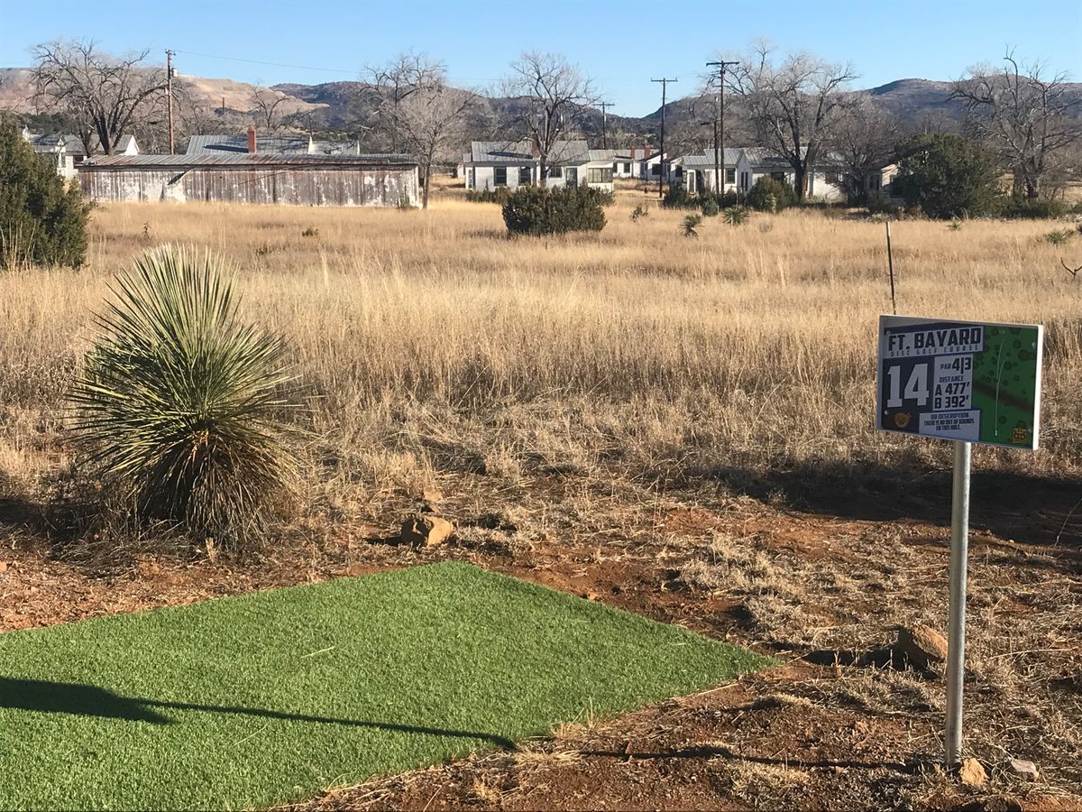 Turf tee pads behind old army barracks housing.