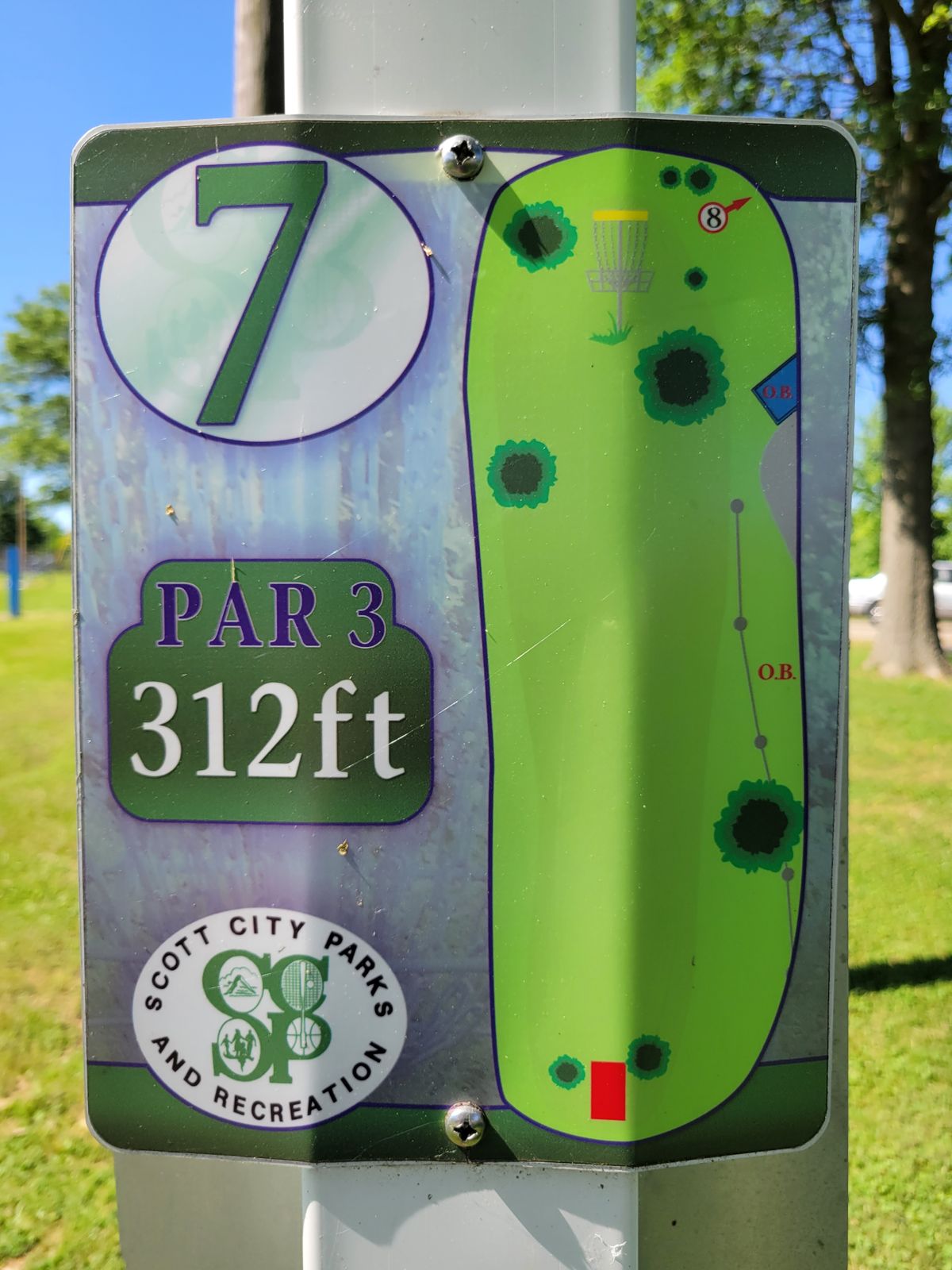 7 sign.  MANDO left of large right tree. 2 pin positions.