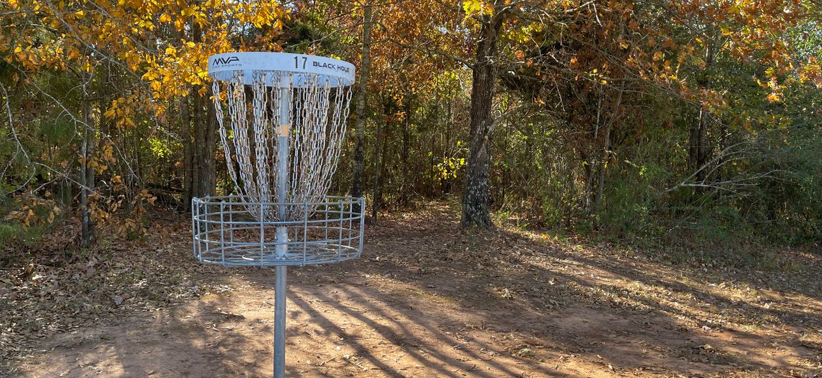 Hole 17 basket, hole 18 Tee-box trail behind it