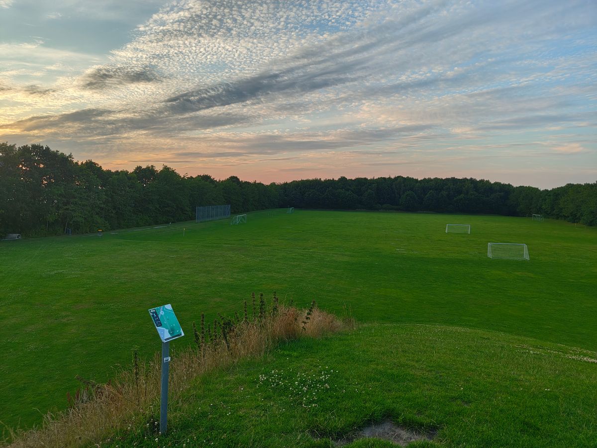 Hole 1 from the top of a hill, with a view of the whole course. Although many of the holes are in the woods all the way in the back.