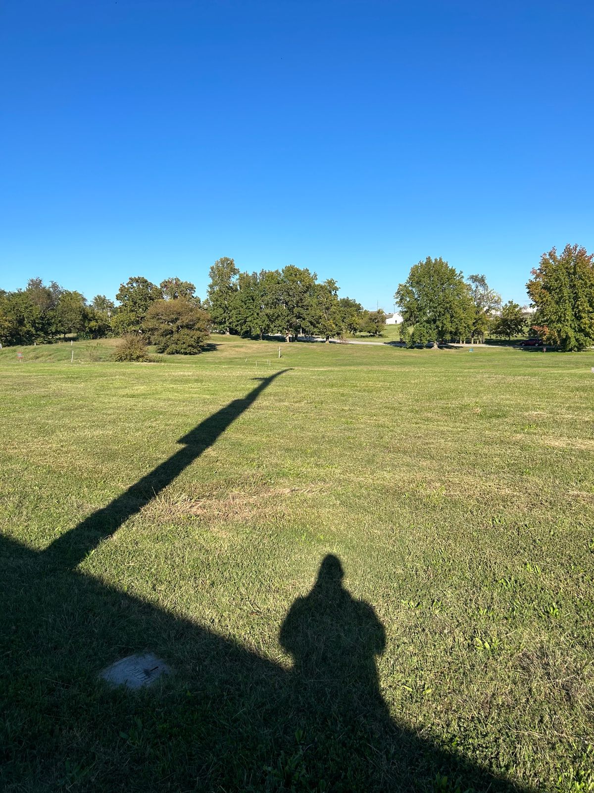Hole #13 Grass Tee Pad. There is no post. Feel free to tee off around this marker in the picture. Near the light post of the baseball field. 
