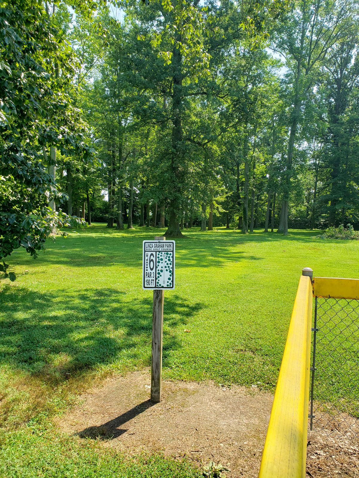 #6 Tee-Off Sign by baseball diamond fence.