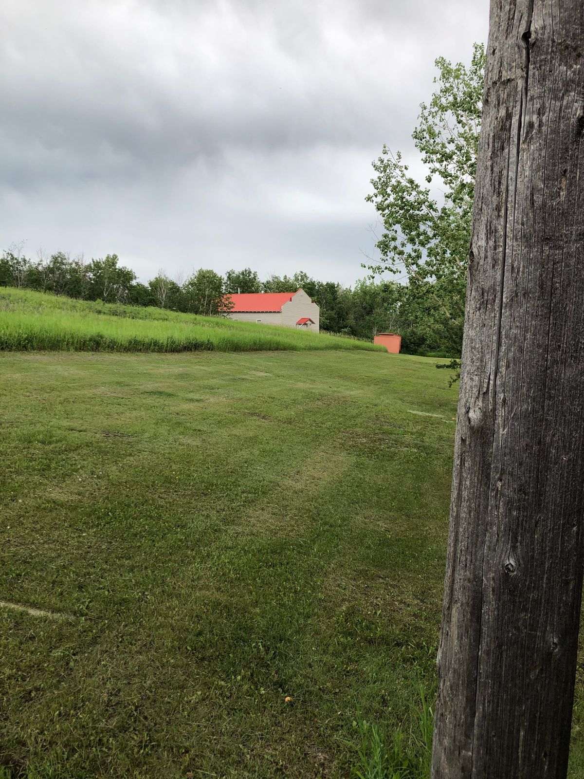 Hole 3 tee off by power pole. Basket curves left past bushes to the rear of community hall building