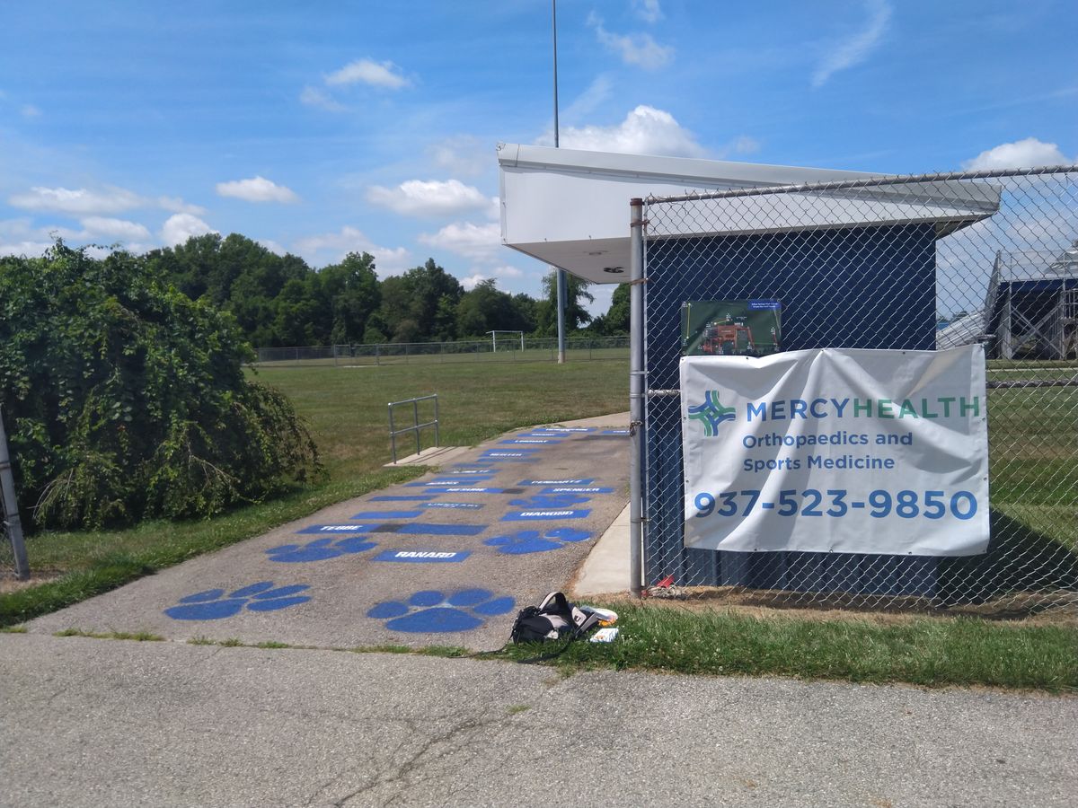 Entrance to first tee (to the right of the path behind the bleachers), map posted on the fence