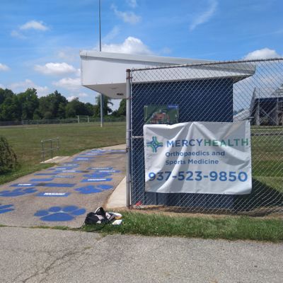 Entrance to first tee (to the right of the path behind the bleachers), map posted on the fence