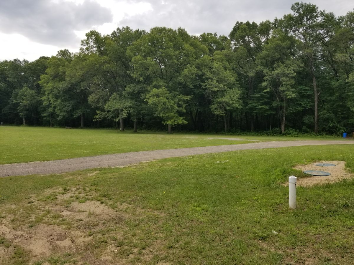 Open look at hole #1 from around #18 exit point (blue barrel near pad, basket leftmost edge of photo)