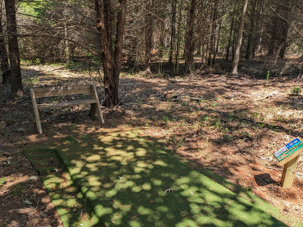The tee pad, bench, and sign at Hole 9.